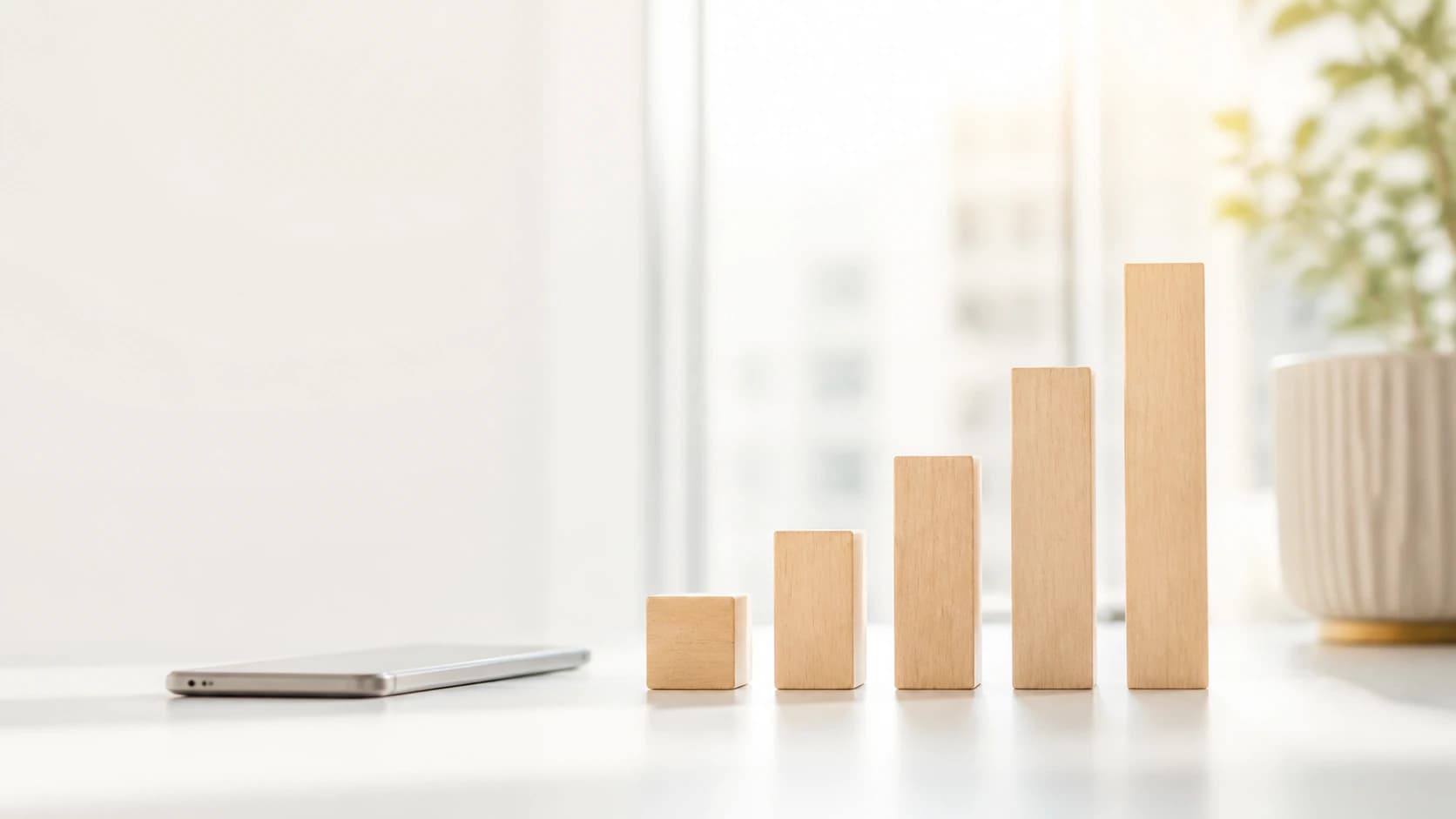 Pale wooden blocks of increasing height standing in a row beside a phone.